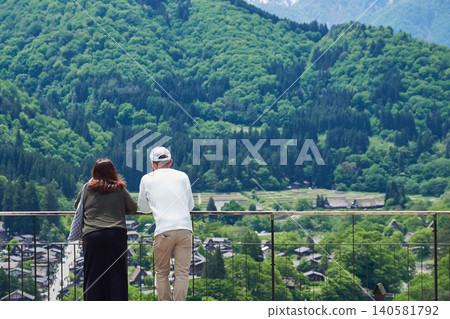 Tourists enjoying the scenery from an observation deck in Shirakawa-go, a World Heritage site and popular tourist spot in early summer. 140581792