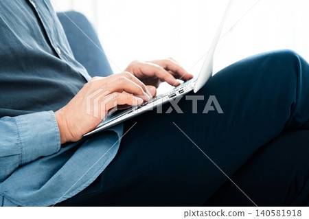 一個男人在客廳裡使用筆記本電腦 140581918