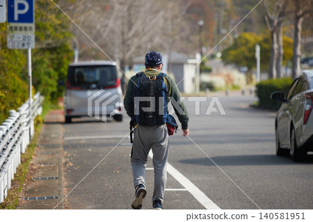 A senior man strolling along a park path in spring. A senior man strolling along a park path in spring. 140581951