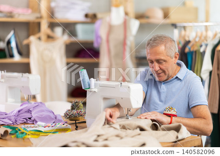 Mature man tailor sewing in workshop Mature man tailor sewing in workshop 140582096
