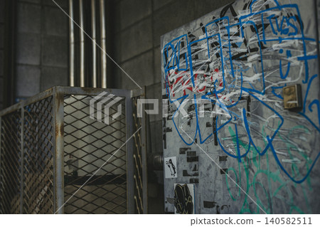 Graffiti-covered power distribution equipment, mesh fence, grunge 140582511