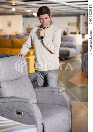 Man in a furniture store chooses an armchair 140582618