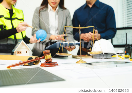 Engineers, architects and legal professionals reviewing building plans with justice scale and gavel, symbolizing construction law, property regulation, contract Engineers, architects and legal professionals reviewing building plans with justice scale and gavel, symbolizing construction law, property regulation, contract 140582633