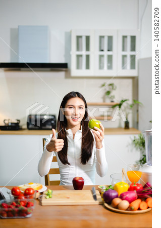 Young woman preparing fresh tomatoes and vegetables in modern kitchen. Healthy cooking, smoothie blender, clean eating, vegan lifestyle and online food blog concept. Young woman preparing fresh tomatoes and vegetables in modern kitchen. Healthy cooking, smoothie blender, clean eating, vegan lifestyle and online food blog concept. 140582709