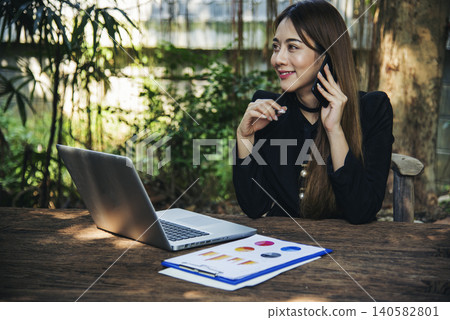 Asian Female freelance using laptop at home office desk. Woman reading financial graph chart Planning analyzing marketing data. Asian female people working office firm with business stuff, coffee cup Asian Female freelance using laptop at home office desk. Woman reading financial graph chart Planning analyzing marketing data. Asian female people working office firm with business stuff, coffee cup 140582801