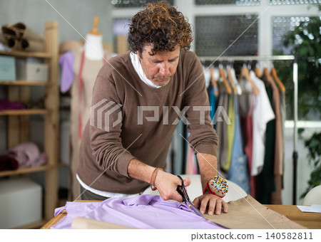 Man cutting fabric in workshop Man cutting fabric in workshop 140582811