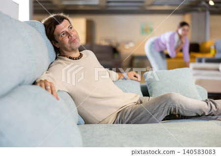 Man looking for sofa in furniture showroom Man looking for sofa in furniture showroom 140583083