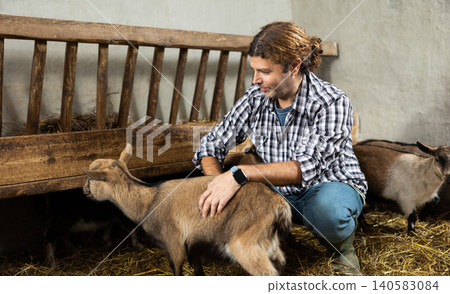 Male worker feeding goats at livestock farm Male worker feeding goats at livestock farm 140583084