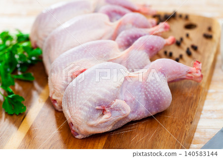 Raw gutted partridges on wooden table with seasonings and greens 140583144