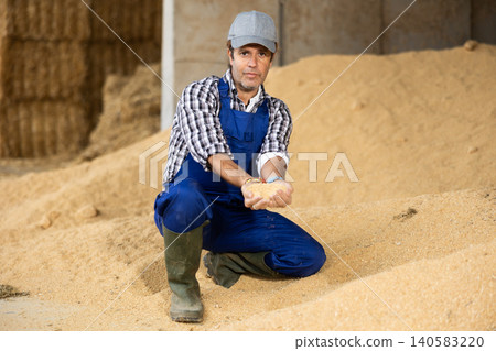 Adult male farmer sitting on pile of soybean husk Adult male farmer sitting on pile of soybean husk 140583220