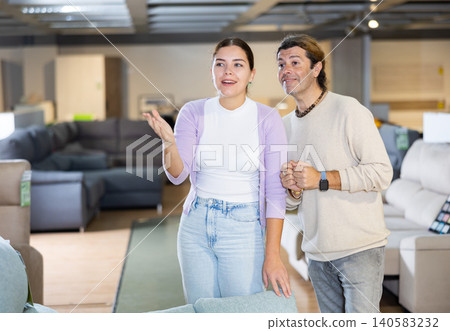 Cheerful couple picking out couch in furniture store 140583232