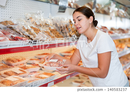 Woman comparing packaged mutton in animal products section of store Woman comparing packaged mutton in animal products section of store 140583237
