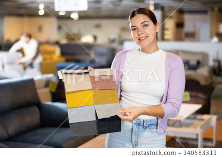 Female furniture salesperson showing different fabric samples in furniture showroom Female furniture salesperson showing different fabric samples in furniture showroom 140583311
