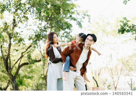 Joyful family enjoying a sunny picnic with music and laughter. Parents and child bonding outdoors, surrounded by love, warmth Joyful family enjoying a sunny picnic with music and laughter. Parents and child bonding outdoors, surrounded by love, warmth 140583341