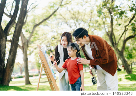 Happy family painting together outdoors in a sunny green park. A joyful lifestyle moment filled with creativity, learning, love, and togetherness. Happy family painting together outdoors in a sunny green park. A joyful lifestyle moment filled with creativity, learning, love, and togetherness. 140583343