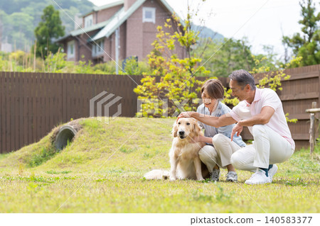 A smiling senior couple enjoying time with their golden retriever in the garden. A smiling senior couple enjoying time with their golden retriever in the garden. 140583377