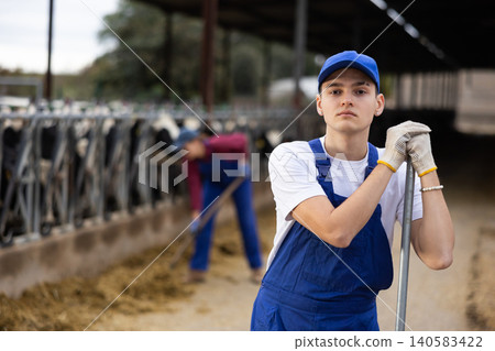 Portrait of positive male farm worker in cowshed Portrait of positive male farm worker in cowshed 140583422