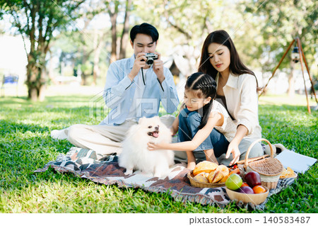 Loving family picnic in a sunny green park with their fluffy dog. A joyful outdoor lifestyle moment full of warmth, nature, and togetherness. Loving family picnic in a sunny green park with their fluffy dog. A joyful outdoor lifestyle moment full of warmth, nature, and togetherness. 140583487