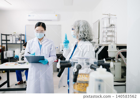 Two professional scientists conducting food quality testing and laboratory analysis in a modern research facility. Two professional scientists conducting food quality testing and laboratory analysis in a modern research facility. 140583562