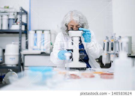 Senior Female Asian Scientist Looking Through Microscope in Modern Laboratory Senior Female Asian Scientist Looking Through Microscope in Modern Laboratory 140583624
