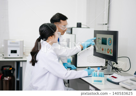 Two Asian Scientists Analyzing Data on Computer Monitor in Modern Laboratory Two Asian Scientists Analyzing Data on Computer Monitor in Modern Laboratory 140583625