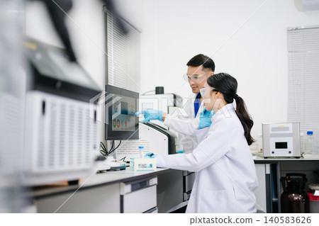 Two Asian Scientists Analyzing Data on Computer Monitor in Modern Laboratory Two Asian Scientists Analyzing Data on Computer Monitor in Modern Laboratory 140583626