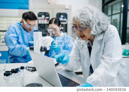 Team of scientists analyzing blue liquid samples in a modern lab, showcasing biotechnology, chemistry, and medical research innovation. 140583638