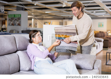 Man presents upholstery samples to a woman Man presents upholstery samples to a woman 140583643
