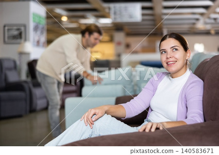 Woman trying out armchair in furniture showroom Woman trying out armchair in furniture showroom 140583671