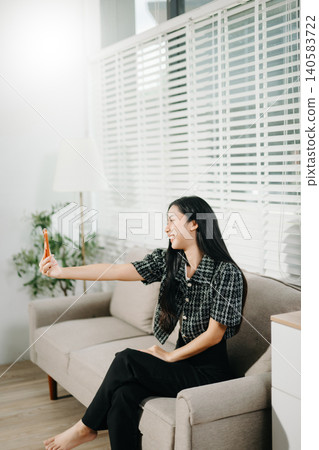 Young asian woman relax on comfortable couch at home texting messaging on smartphone and tablet smiling girl use cellphone shopping online from home Young asian woman relax on comfortable couch at home texting messaging on smartphone and tablet smiling girl use cellphone shopping online from home 140583722