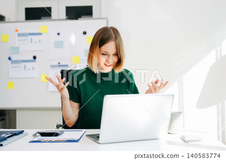 Business woman reacting during a video call while working on a laptop in a bright modern office. 140583774