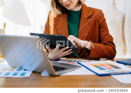 Female designer choosing a color palette while working on a creative project in a bright modern workspace. Female designer choosing a color palette while working on a creative project in a bright modern workspace. 140583804