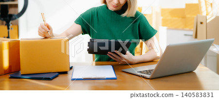 Small business owner packing online orders at home using tablet and boxes. Ecommerce, startup, online seller, shipping and order Small business owner packing online orders at home using tablet and boxes. Ecommerce, startup, online seller, shipping and order 140583831