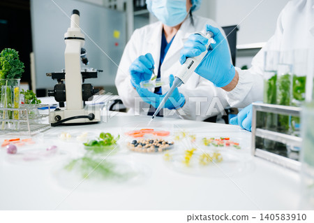Scientists conducting biotechnology research in laboratory, testing plant and food samples for GMO analysis, nutrition safety, pharmaceutical development and innovation. Scientists conducting biotechnology research in laboratory, testing plant and food samples for GMO analysis, nutrition safety, pharmaceutical development and innovation. 140583910