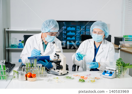 Dynamic scene of food scientists using microscopes and pipettes in a lab Dynamic scene of food scientists using microscopes and pipettes in a lab 140583969