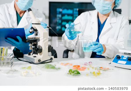 Dynamic scene of food scientists using microscopes and pipettes in a lab Dynamic scene of food scientists using microscopes and pipettes in a lab 140583970