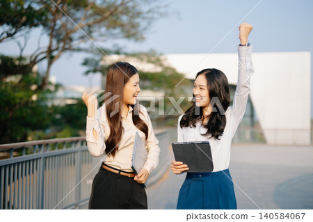 Asian businesswomen celebrating success with a handshake, symbolizing partnership, teamwork, and business deal achievement in corporate environment. Asian businesswomen celebrating success with a handshake, symbolizing partnership, teamwork, and business deal achievement in corporate environment. 140584067