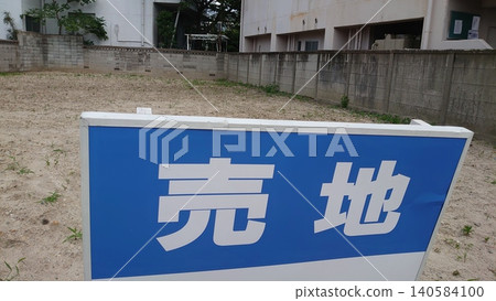 A blue "For Sale" sign is placed in an empty lot surrounded by ropes. 140584100
