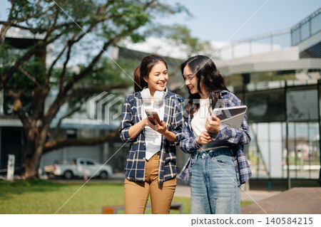 Asian students using smartphone and tablet at modern campus. Social media, digital communication, online networking and Gen Z lifestyle in university setting. Asian students using smartphone and tablet at modern campus. Social media, digital communication, online networking and Gen Z lifestyle in university setting. 140584215