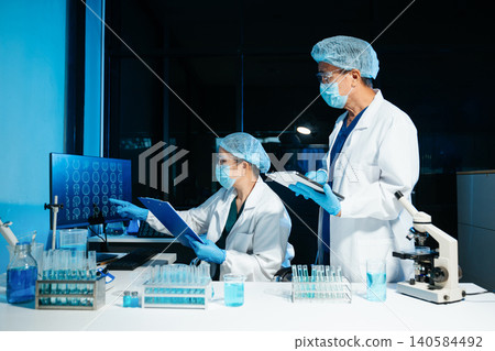 Medical scientists working in laboratory using microscope and analyzing brain scan data for diagnostics and research, reflecting healthcare technology and professional laboratory environment. Medical scientists working in laboratory using microscope and analyzing brain scan data for diagnostics and research, reflecting healthcare technology and professional laboratory environment. 140584492