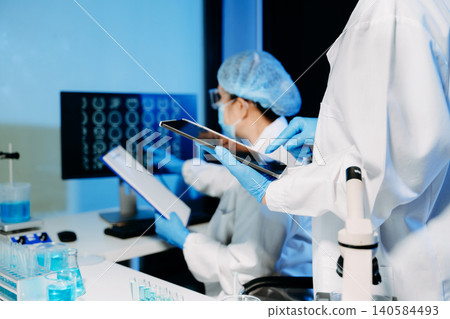 Medical scientists conducting laboratory research using digital tools and lab equipment. Healthcare, biotechnology, diagnostics, and clinical research teamwork concept. 140584493