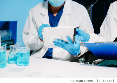 scientists in lab coats conducting research, handling glassware, and working with chemicals in a modern, high tech laboratory. scientists in lab coats conducting research, handling glassware, and working with chemicals in a modern, high tech laboratory. 140584521