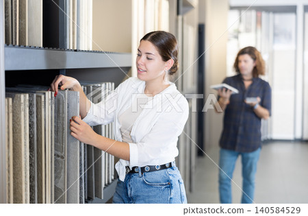 Satisfied young woman carefully chooses ceramic flooring for her apartment in hardware store Satisfied young woman carefully chooses ceramic flooring for her apartment in hardware store 140584529