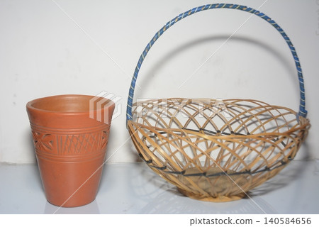 Rustic brown clay cup and empty woven wicker basket with blue handle, container 140584656