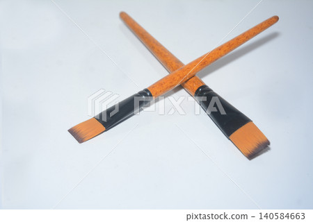 Pair of artist paintbrushes crossed on a white background with paintbrush Pair of artist paintbrushes crossed on a white background with paintbrush 140584663