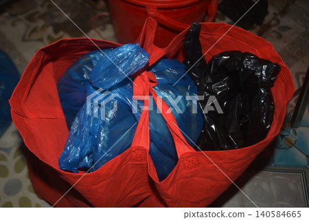 Red reusable fabric shopping tote bag containing plastic grocery bags Red reusable fabric shopping tote bag containing plastic grocery bags 140584665