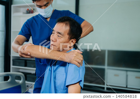 Physiotherapist assisting senior patient with shoulder rehabilitation in hospital clinic. Healthcare, recovery, pain relief and elderly mobility 140584818