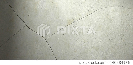 Close up of a light grey concrete wall texture with natural cracks spreading across its surface. Close up of a light grey concrete wall texture with natural cracks spreading across its surface. 140584926