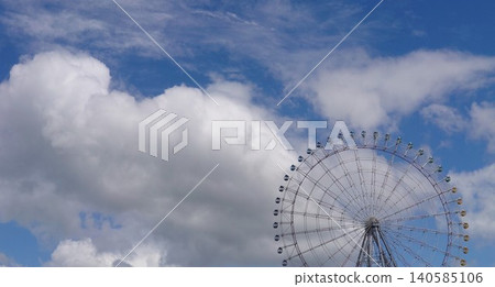 A large Ferris wheel stands out against the blue sky, and the vibrant white clouds of summer. A large Ferris wheel stands out against the blue sky, and the vibrant white clouds of summer. 140585106