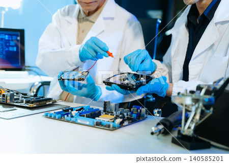 Technicians repairing hard drive and computer hardware in technology lab, focusing on data recovery, diagnostics, and electronic maintenance Technicians repairing hard drive and computer hardware in technology lab, focusing on data recovery, diagnostics, and electronic maintenance 140585201